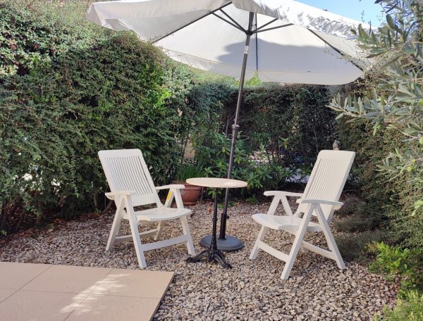 Deux chaises de jardin confortables, disposées à l'ombre d'un parasol, parfaites pour se détendre en extérieur.
